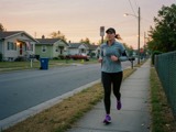 An adult jogging on a neighborhood sidewalk at dawn