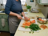 An adult chopping carrots on a home kitchen counter