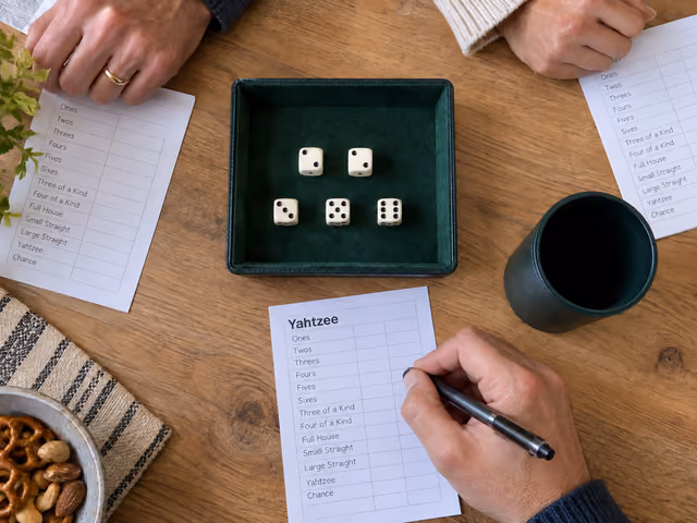 A player prepares to record a Yahtzee roll beside five dice and blank scorecards