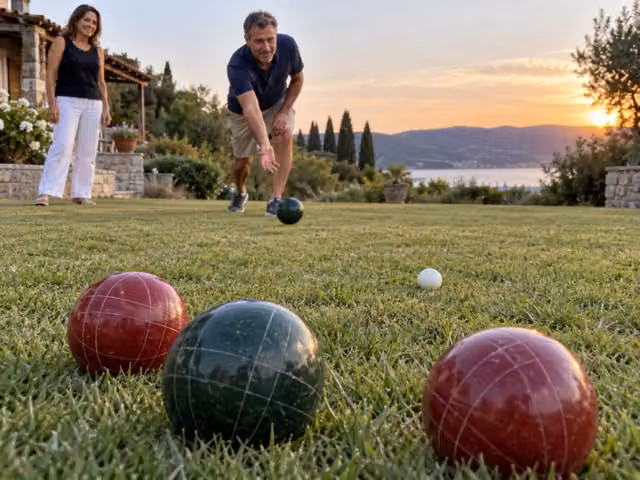 Adults rolling bocce balls toward one small white pallino
