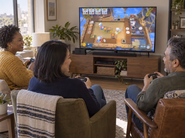 Three adults play a cooperative cooking game with controllers and a shared television.