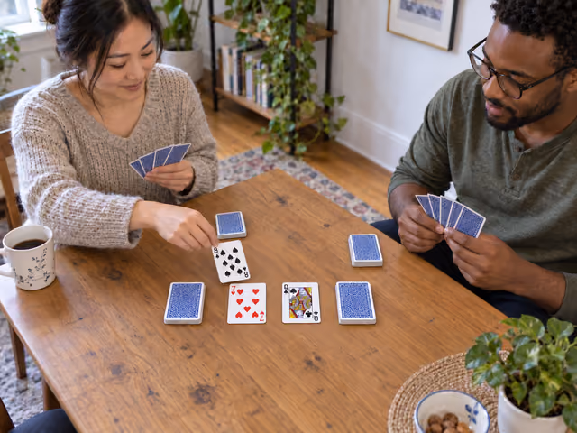 Two adults playing five-card-hand Speed with two shared middle piles and face-down reserves.