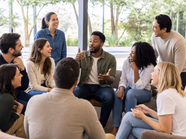Friends seated in a circle listening to a speaker.