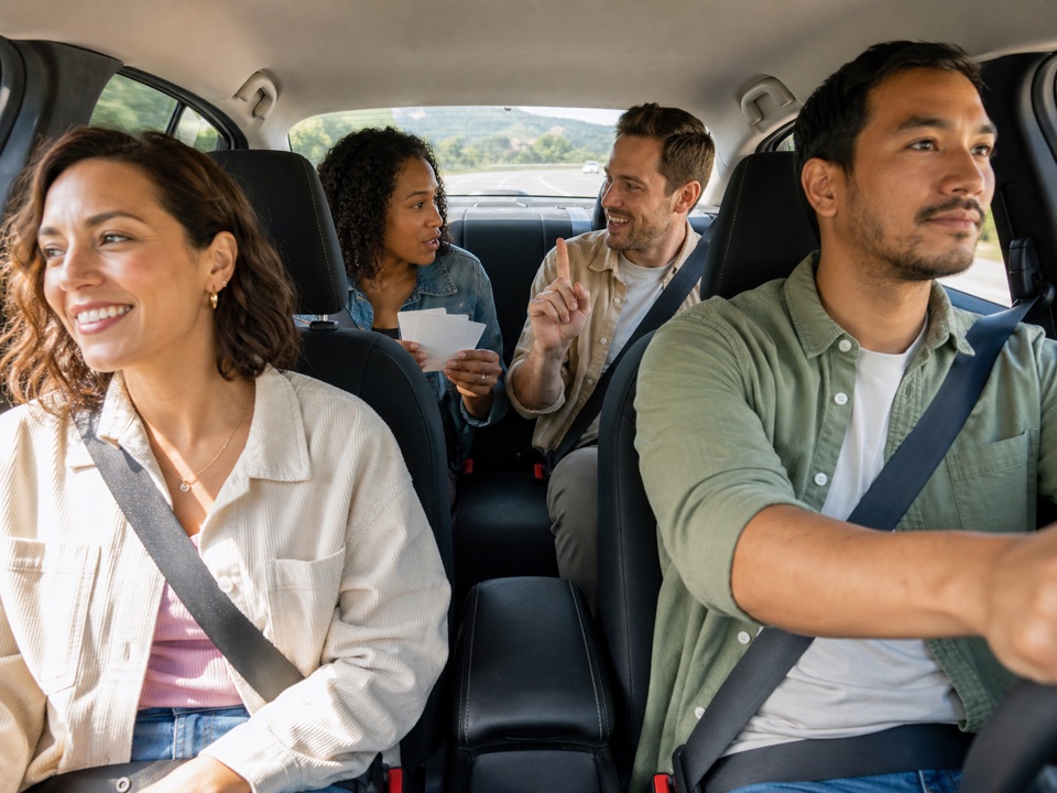 Adults playing a trivia game in a car on a road trip