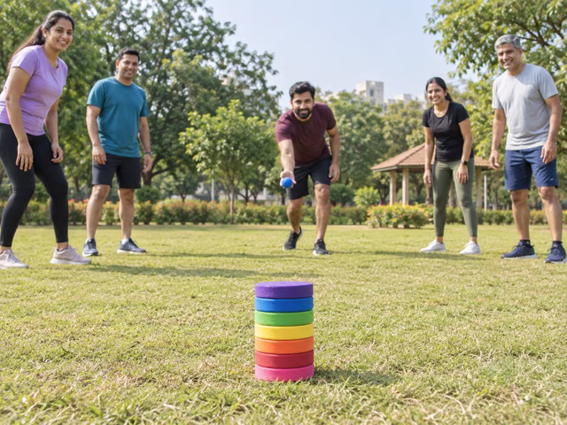 Adults playing near a stack of seven flat discs with a soft ball.