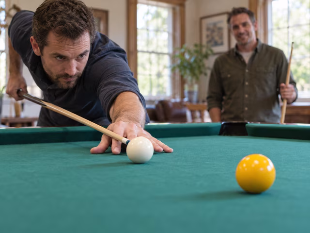 A cue aligned behind a white ball beside a plain yellow ball on green baize.